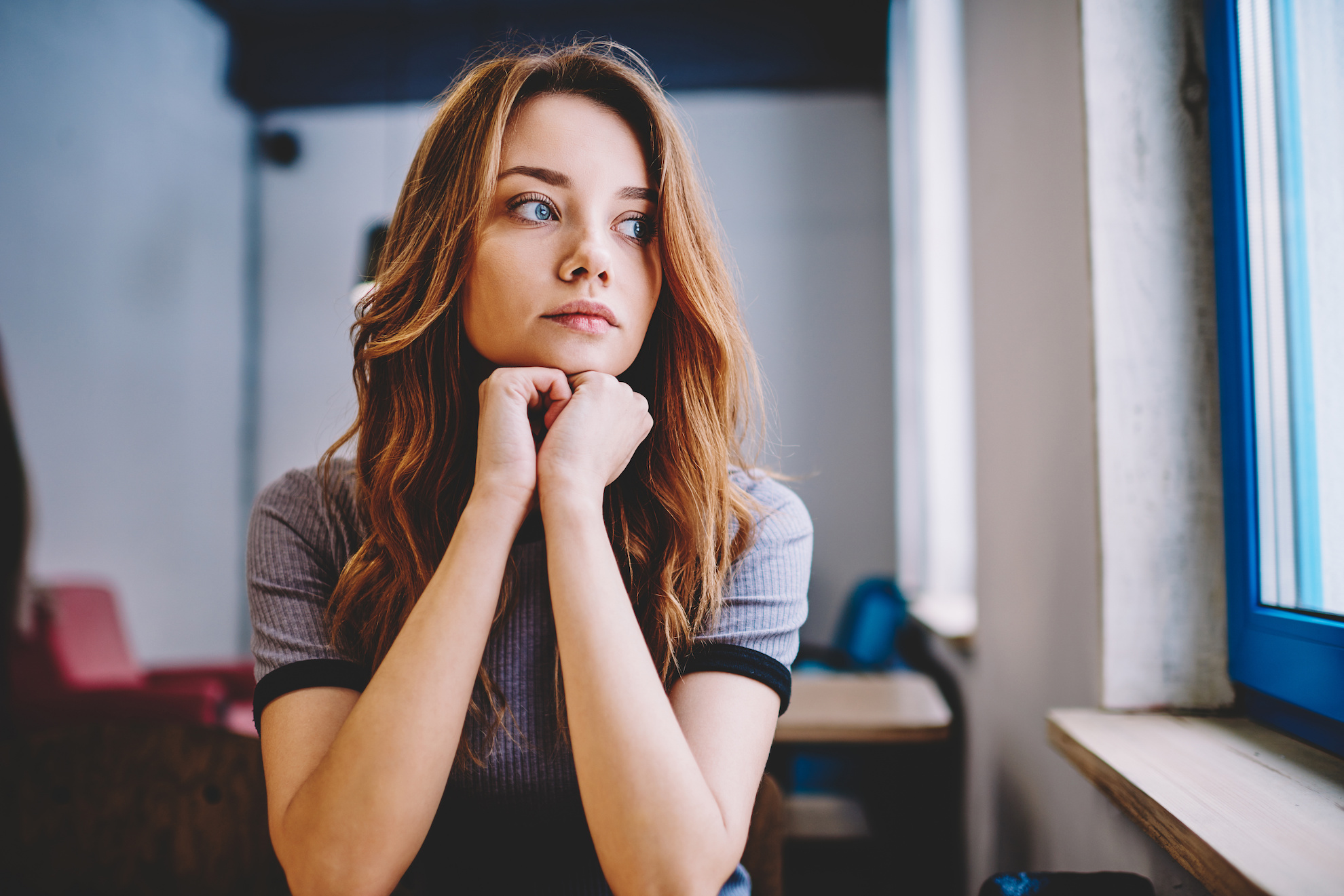 Woman resting head on crossed arms with a concerned look.